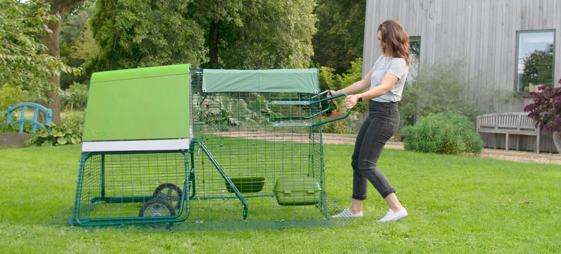 Een vrouw die een Eglu Go kippenhok verplaatst