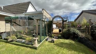 De tuin Omlet catio verbonden door een loopbrug met het dek Omlet veranda op een hoger niveau. (2 extra panelen, afzonderlijk verkocht, waren nodig om de achterkant van de veranda af te dichten)