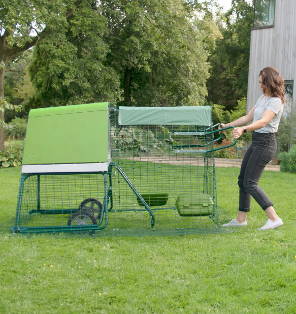 Vrouw verplaatst het Eglu Go verplaatsbaar kippenhok in haar achtertuin